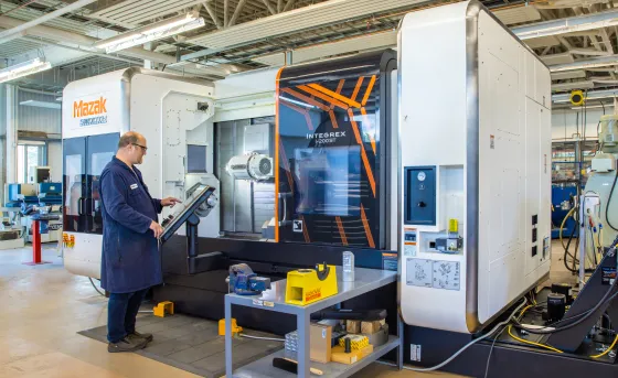 A technician operates a large Mazac printer in CIM-TAC research facility.