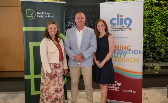Dr. Tonya WOlfe, Tony Weeks, and Catherine Laing stand smiling in front of RDP and CLIQ banners