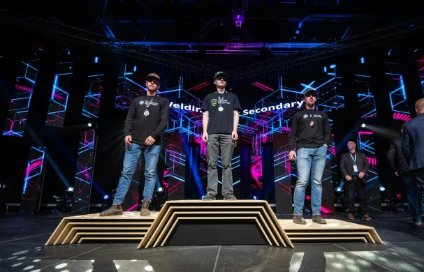 Lucas Stang (RDP Welding student) stands with his gold medal on a podium with two other welders at Skills Canada Alberta 2025