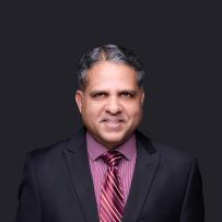 Smiling headshot of Raf Mohammed in a dark suit and a burgundy shirt and tie 