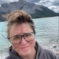 A selfie. Dawn squints into the camera, the wind blowing her hair as she stands in front of a lake in the mountains