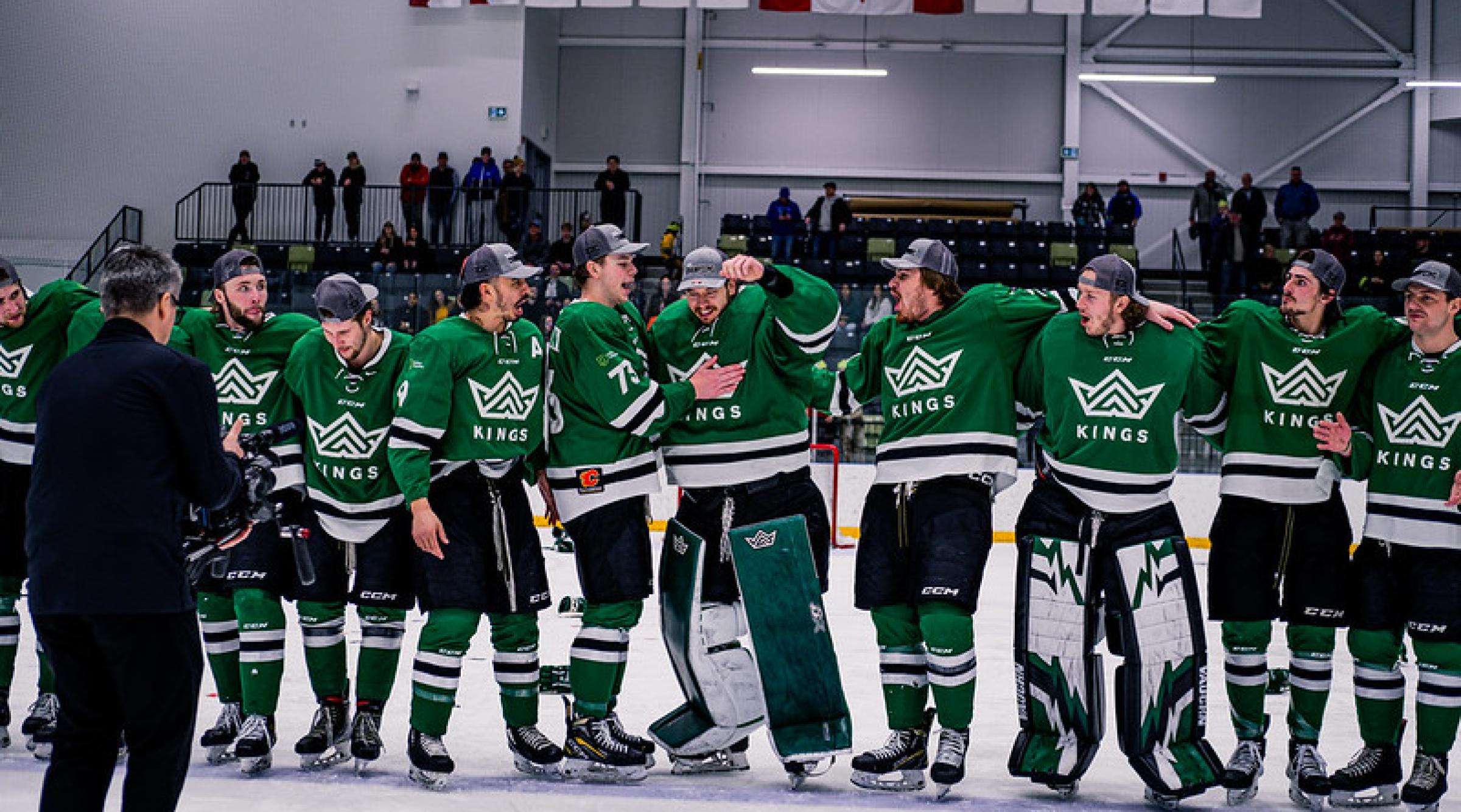 Kings hockey players surrounding and celebrating their goalie on the ice