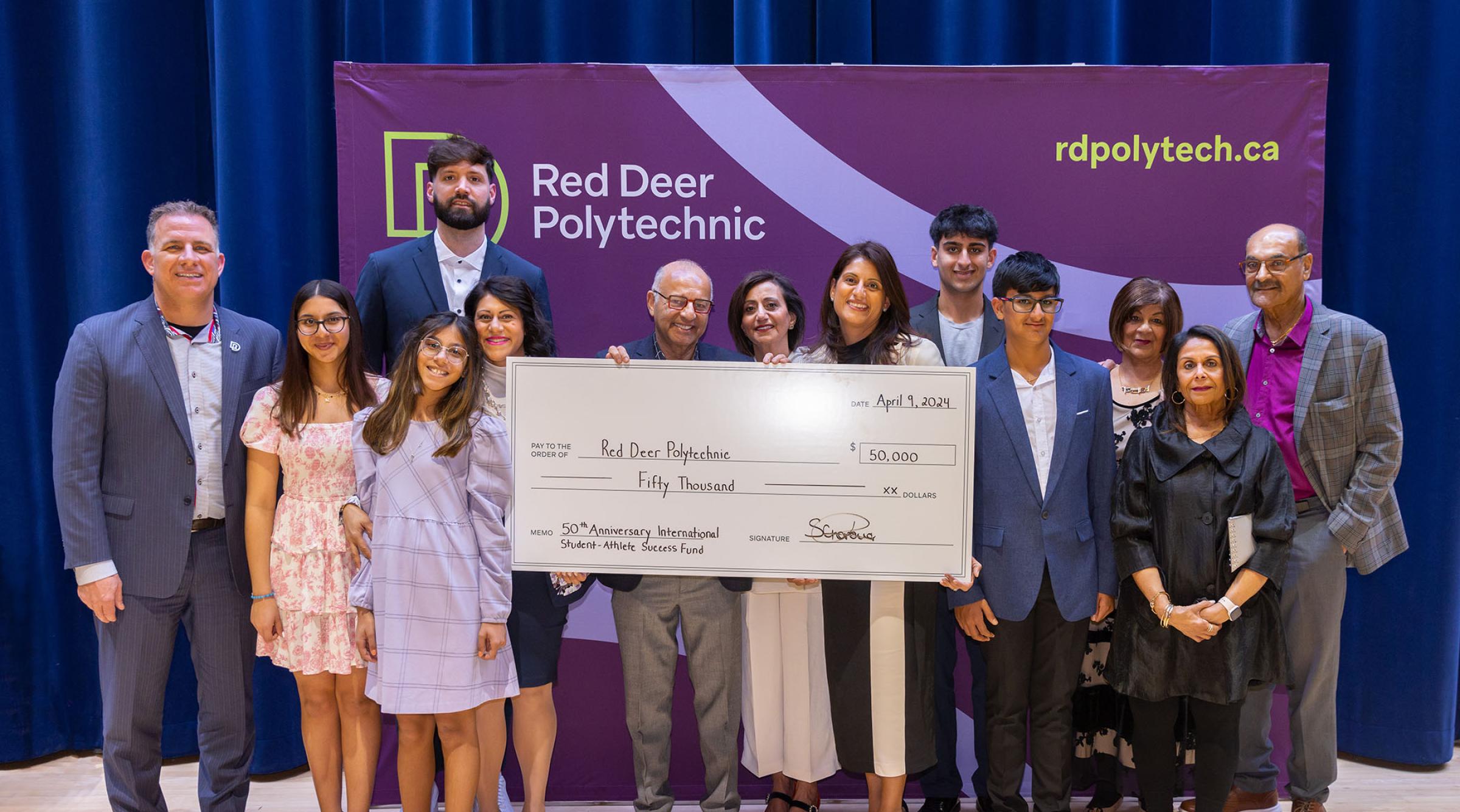 A group shot of smiling members of the ZS Holdings group with RDP President. The group holds a cheque for $50,000