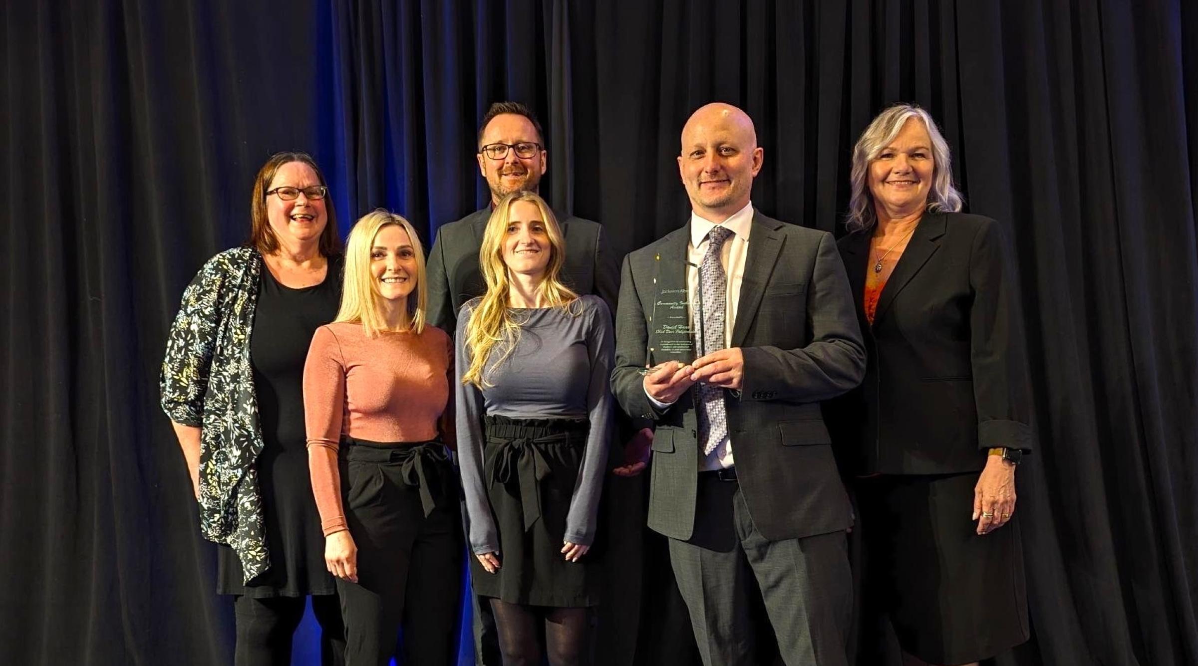 Dan Haas receiving the Community Inclusion Award on stage with a few other group members