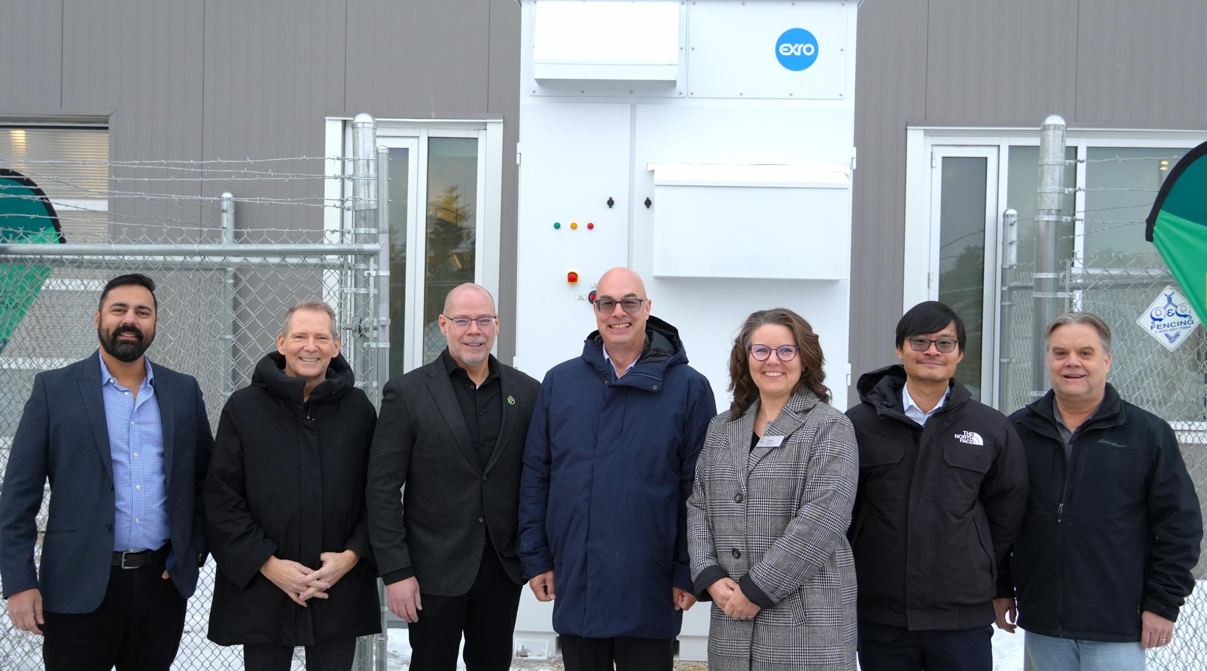 A group of representatives from RDP and Exro Technologies stands outside in front of the First Cell Driver Energy Storage System