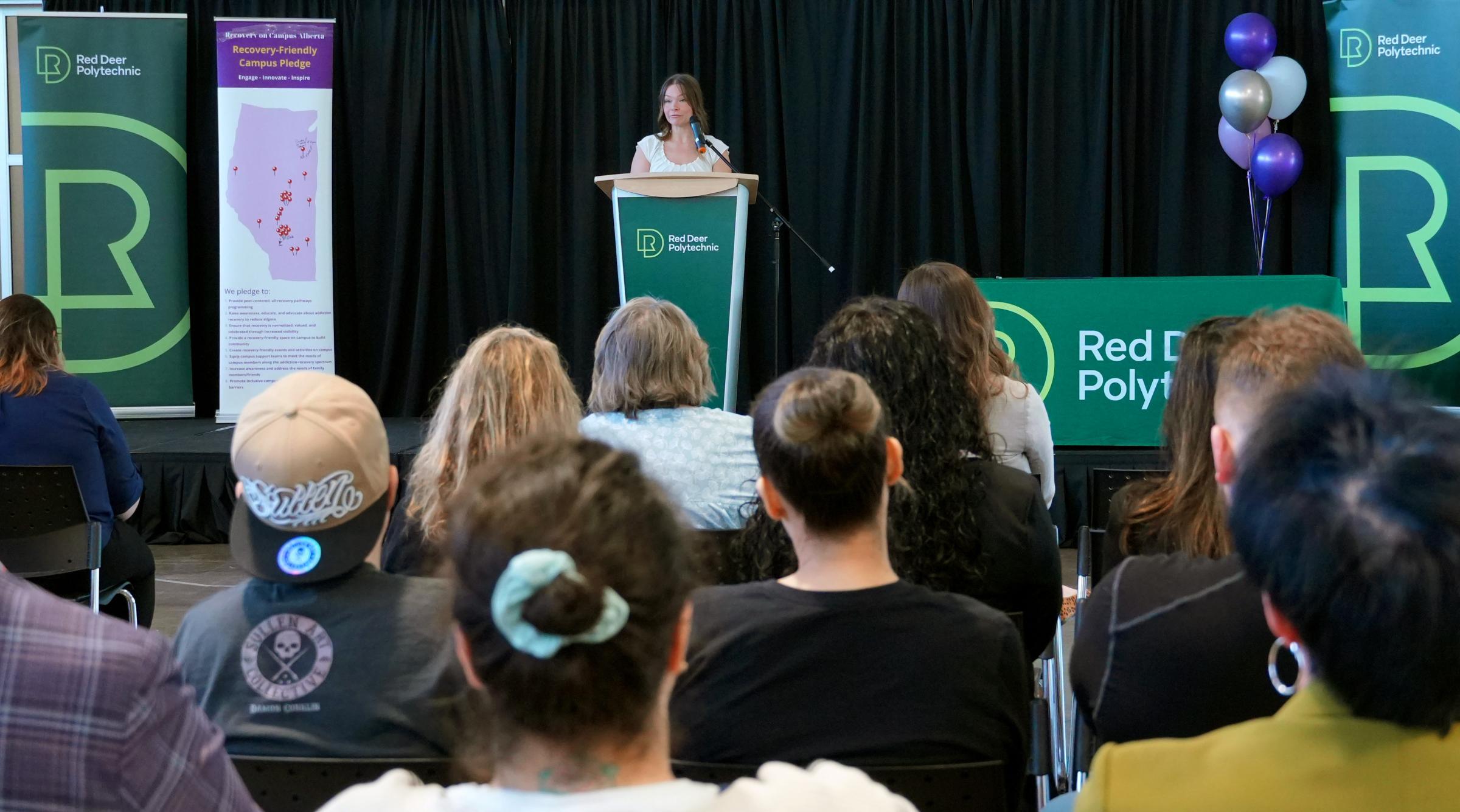 An RDP student addresses an audience from a podium at the Recovery on Campus event