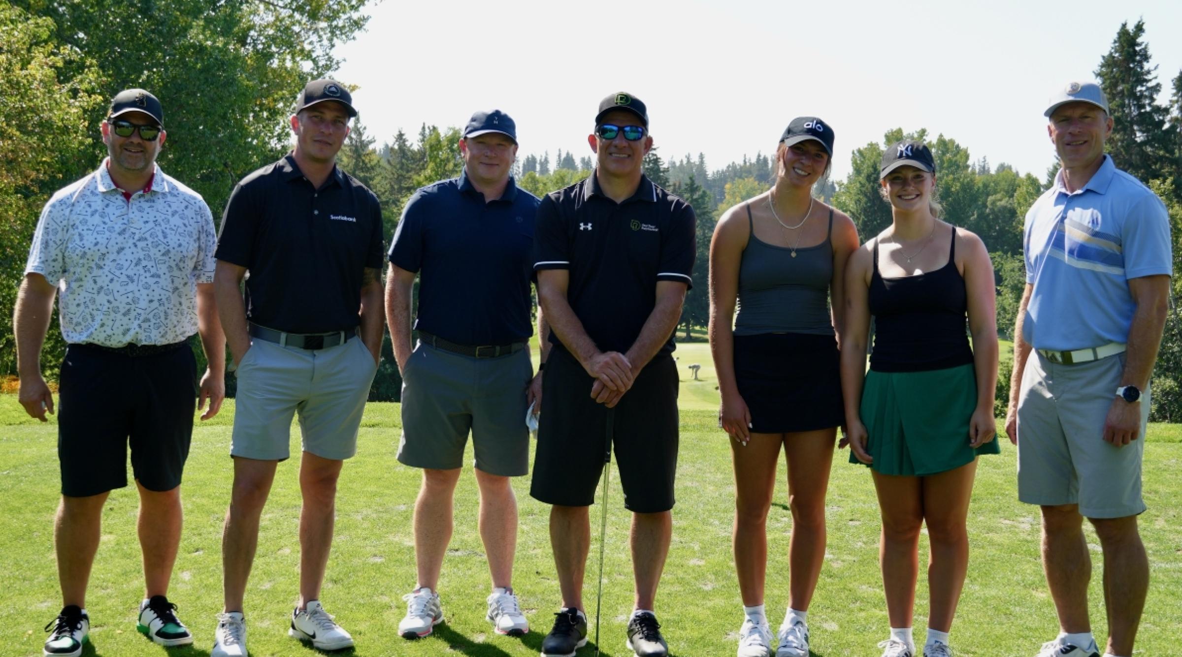 A group of golfers, student athletes, and RDP President Stuart Cullum standing on a fairway