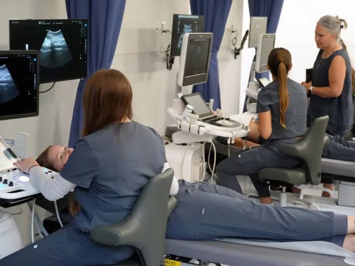 Students in grey scrubs practice using the new sonography equipment in RDP's new lab