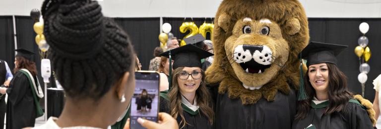 Graduates pose for photo with RDP's mascot, Rufus, before ceremony