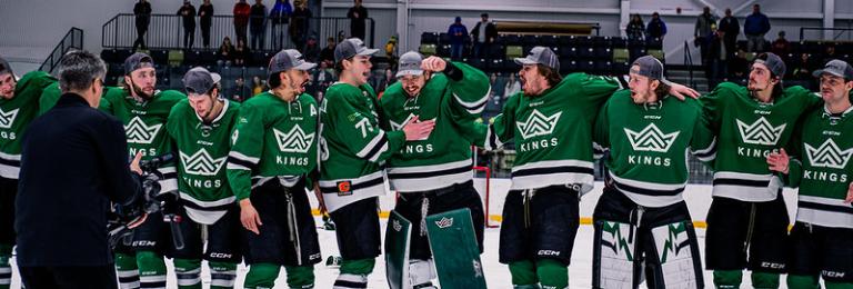 Kings hockey players surrounding and celebrating their goalie on the ice