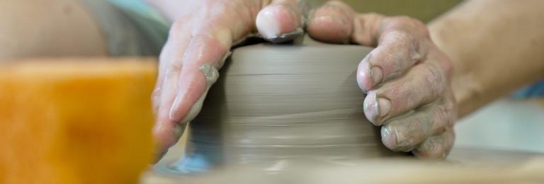Close up of hands forming clay on a potter's wheel