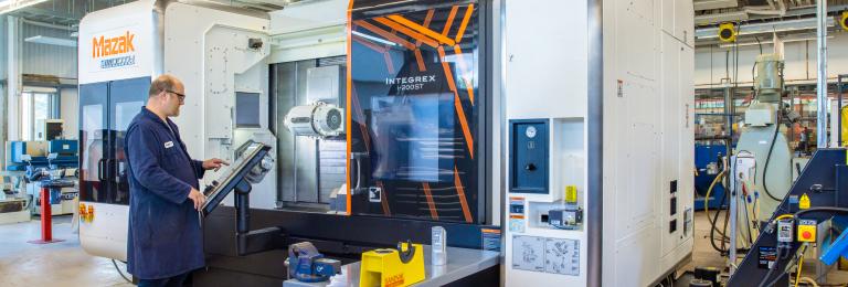 A technician operates a large Mazac printer in CIM-TAC research facility.