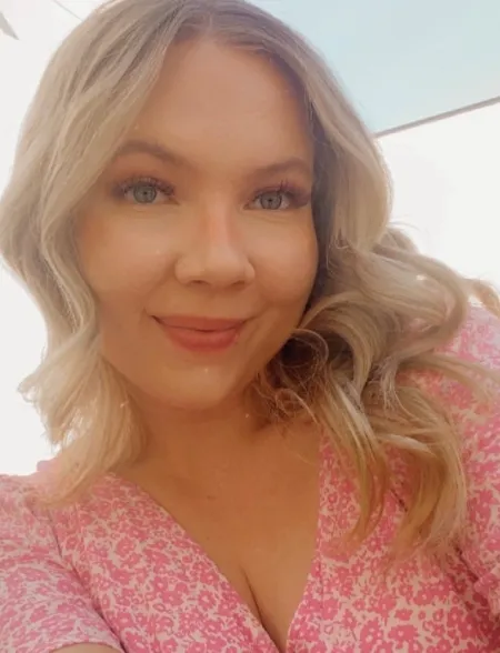 Haley smiles at the camera wearing a prink dress against a bright white background