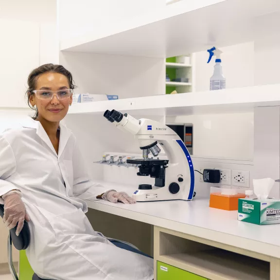 Indigenous Female smiling sitting by microscope