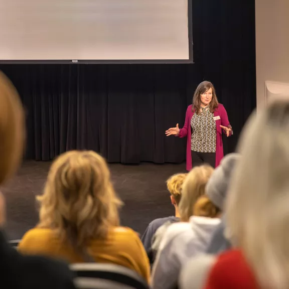 Instructor at the front of class with theatre seating.