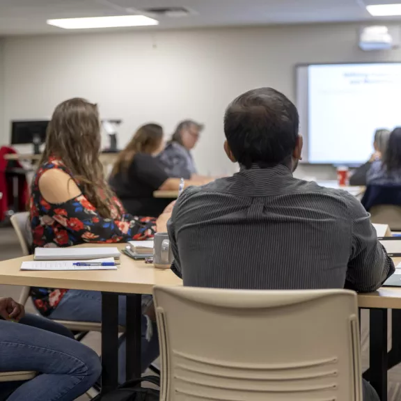 Large classroom with mature students facing the instructor at the front of class.