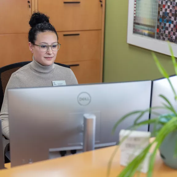 An admin professional working at a desk with two computer monitors.