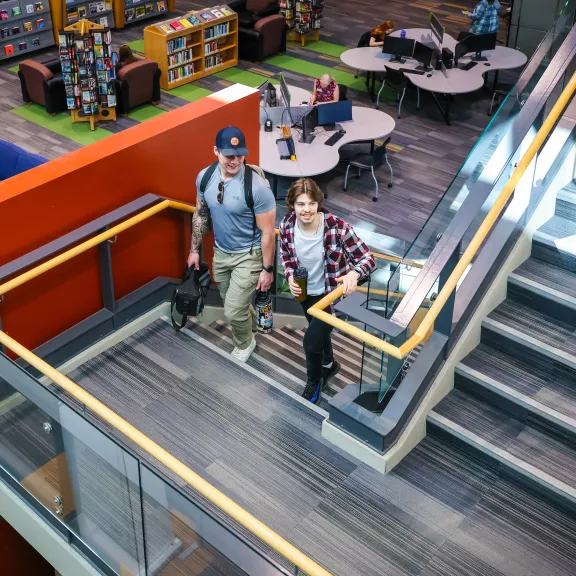 Two students walking up the stairs in the library.