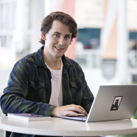 Student working on a laptop looking at the camera.