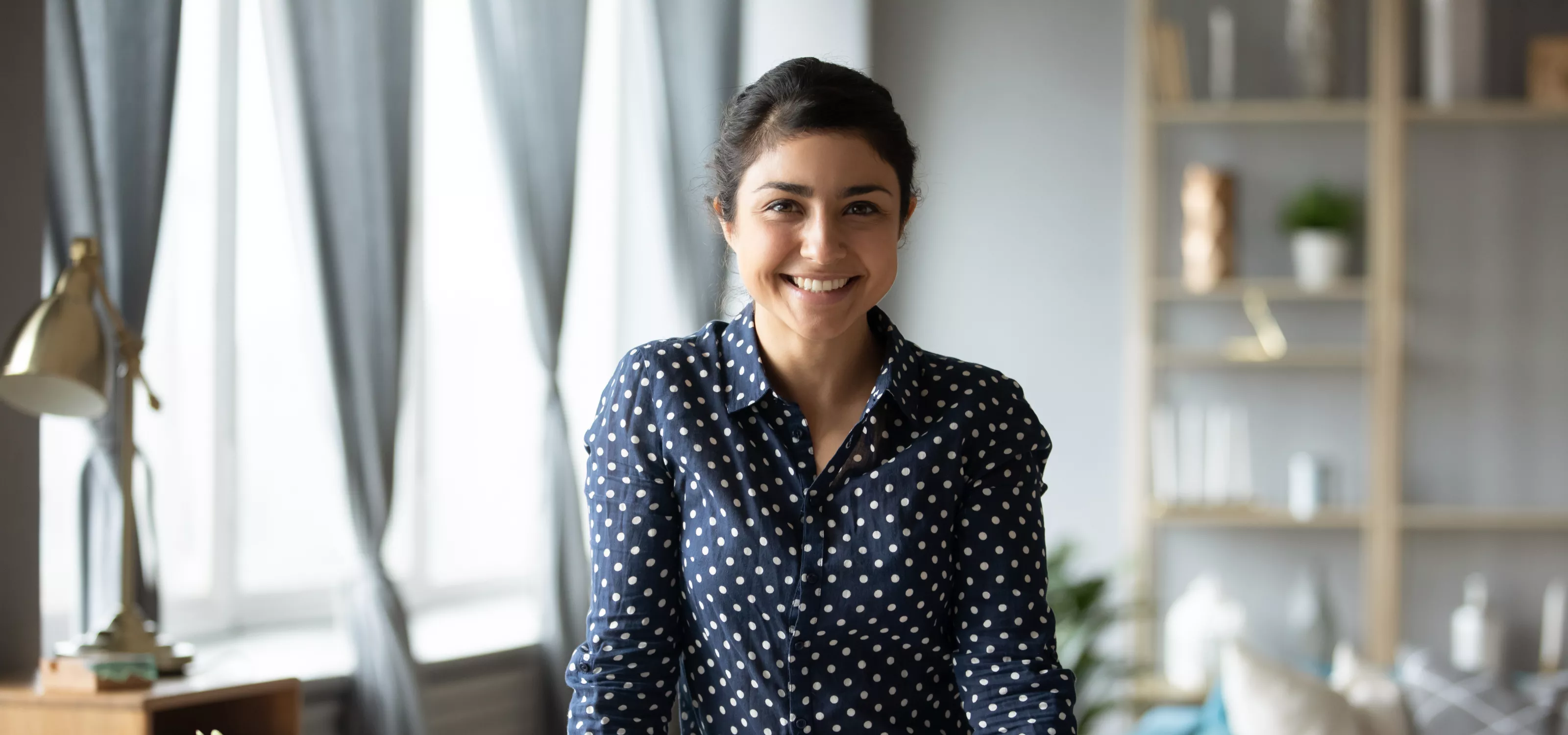 Young woman standing at desk looking at the camera.