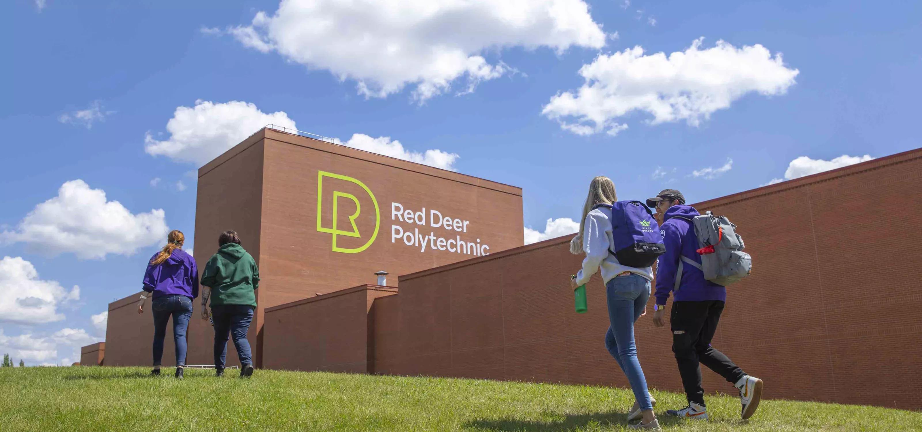 Four students walking outdoors with the Art Centre in the background.