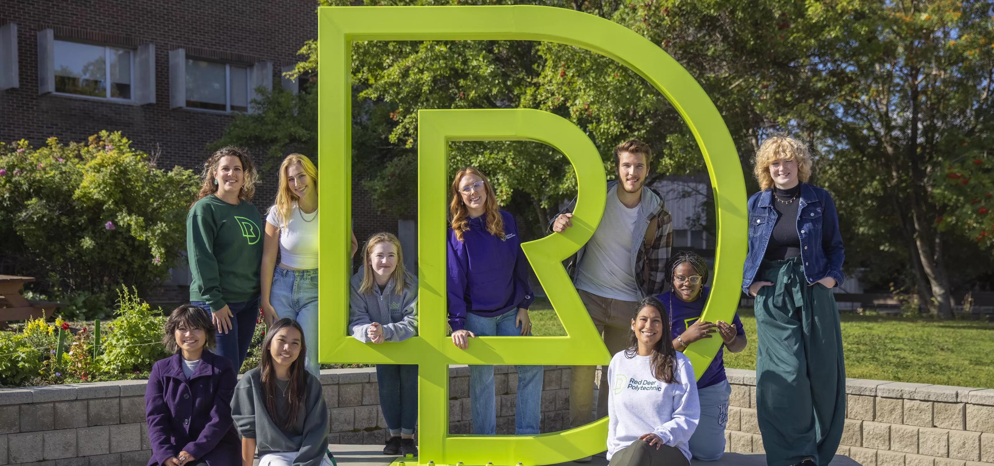 Students sitting by RDP sculpture outside main campus entrance