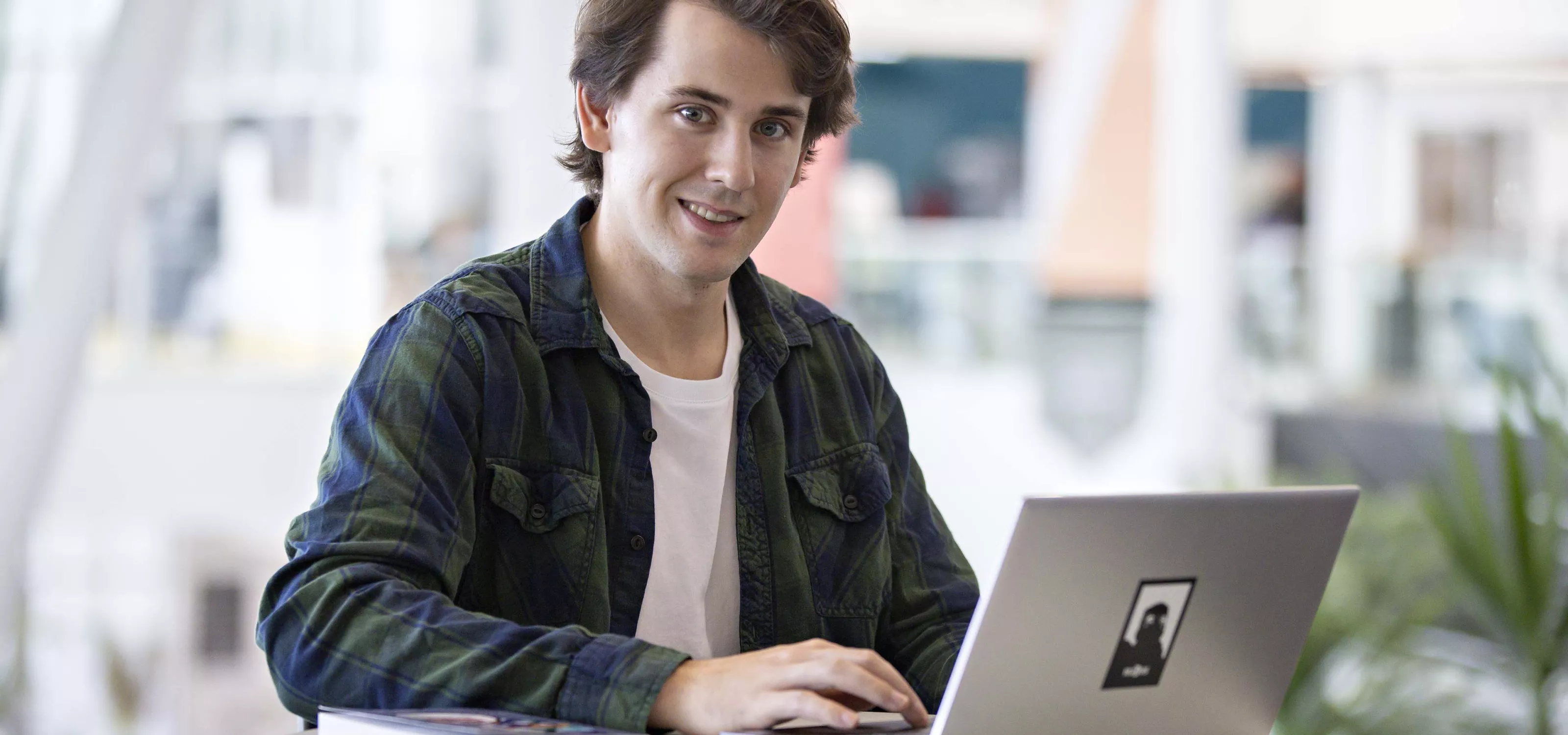 Student working on a laptop looking at the camera.